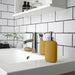 IKEA EKOLN dark yellow soap dispenser styled on modern bathroom sink countertop
