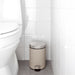 IKEA EKOLN beige waste bin with soft-close lid placed near white bathroom vanity