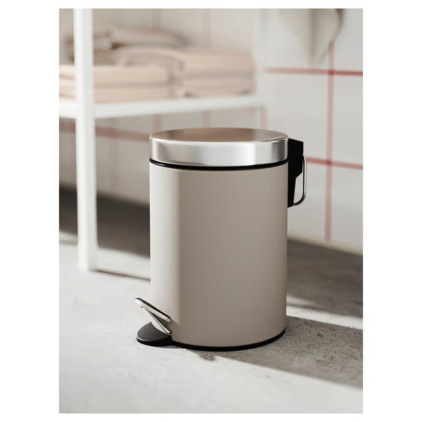 IKEA EKOLN beige cylindrical waste bin with foot pedal beside white toilet