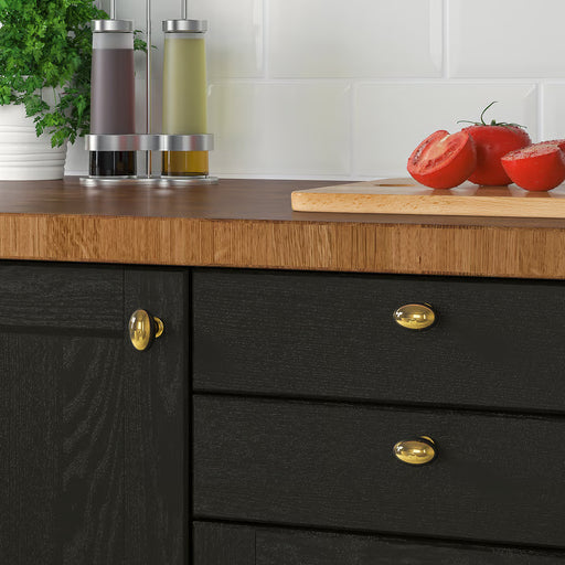 IKEA ENERYDA brass knobs on black kitchen cabinet with wooden countertop, tomatoes and herbs