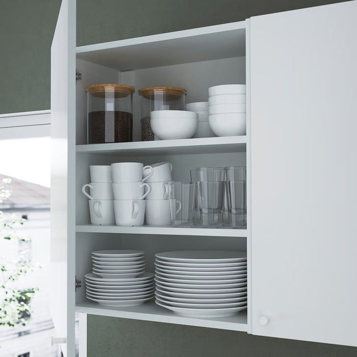 IKEA ENHET white wall cabinet with adjustable shelves holding cups, glasses, bowls and jars