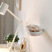 Wall-mounted shelf with glasses next to a desk lamp and stationery items.