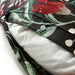 Close-up of a pillow inside a floral-patterned pillowcase with red, green, and white colors on a black background, secured with white buttons.50511635