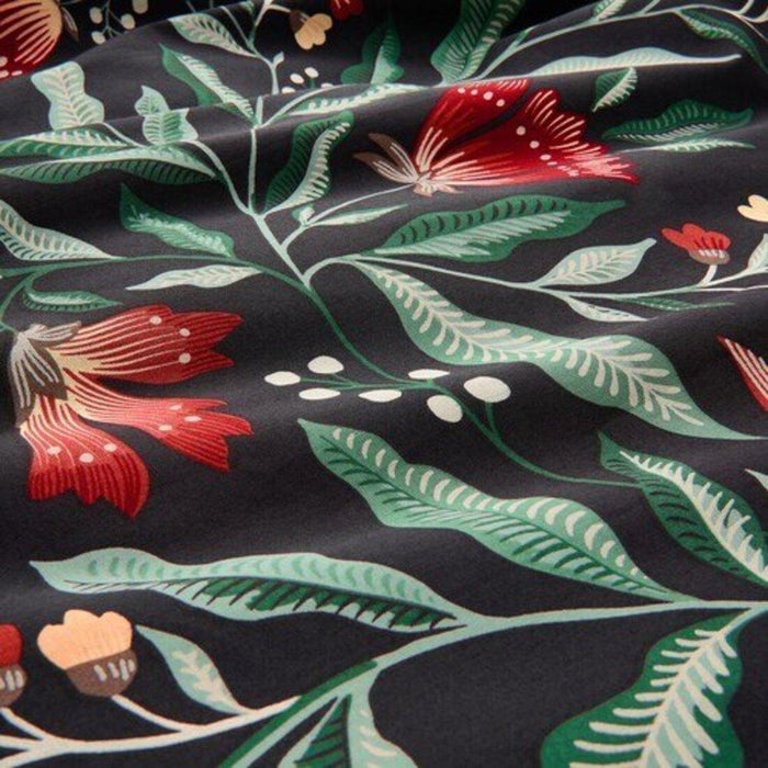 "Close-up of the IKEA SAMMETSBLAD duvet cover showing a detailed floral pattern in red and yellow, with green leaves and white buds on a dark background.50511635

