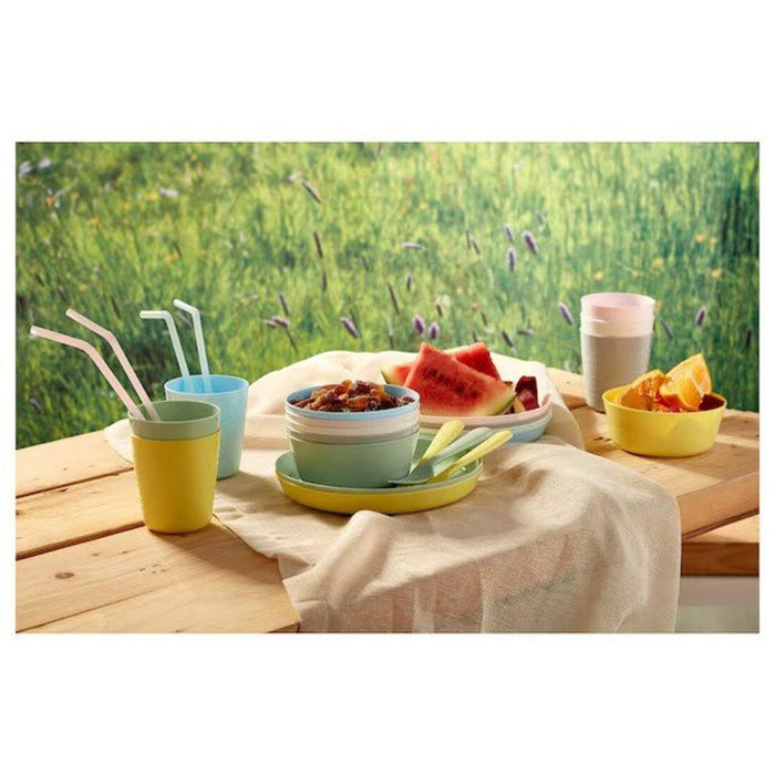 Outdoor setting with colorful tableware on a wooden table against a grassy background