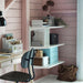 Small home office with a desk, chair, and storage shelves against a pink wall.