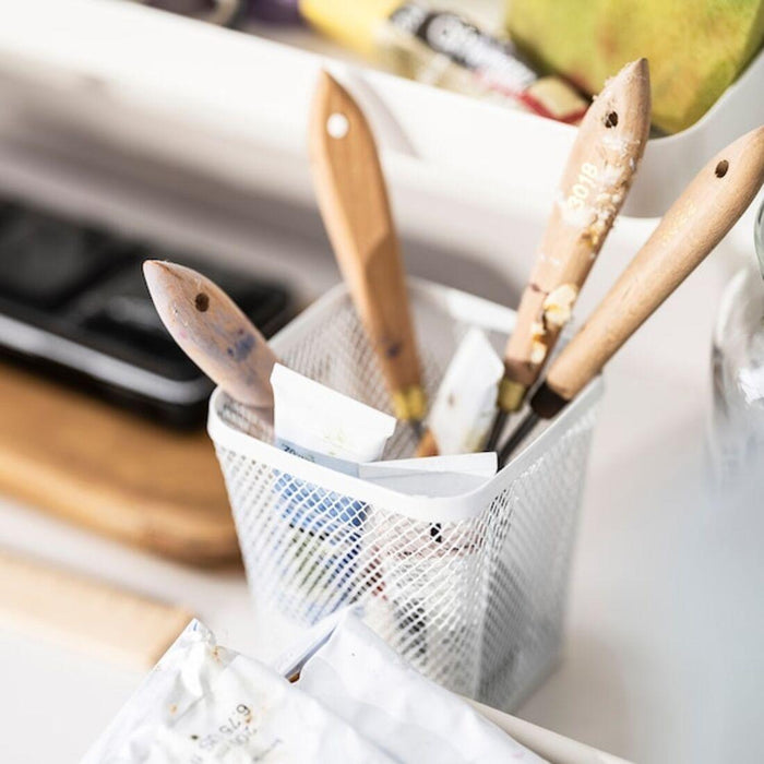 Set of wooden utensils in a mesh basket on a kitchen counter