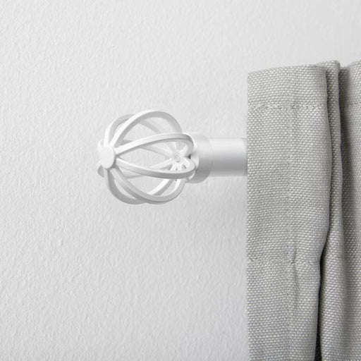 A pair of white IKEA TALLBARSMAL finials on a curtain rod.