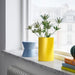 A modern and stylish yellow vase with a curved design, perfect for displaying plants.