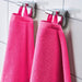 A close-up image of a simple and classic pink hand towel hanging on a bathroom hook