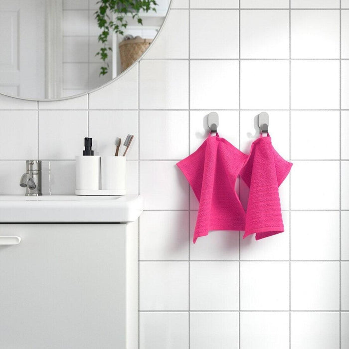 The cloth is neatly folded and placed on a wooden bathroom shelf, and its stylish color adds a pop of brightness to the scene.