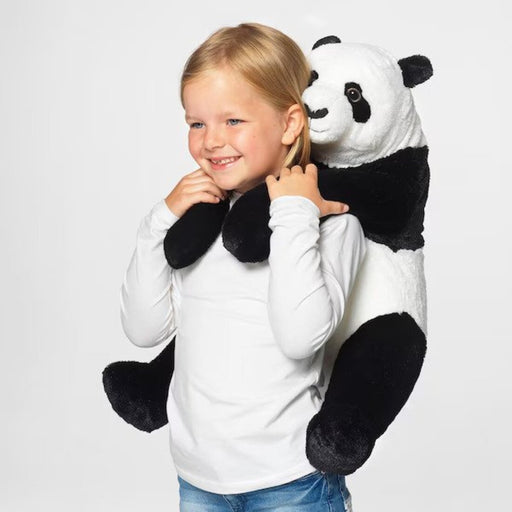 The IKEA Soft Toy Panda sitting on a couch with a child, hugging and cuddling it.