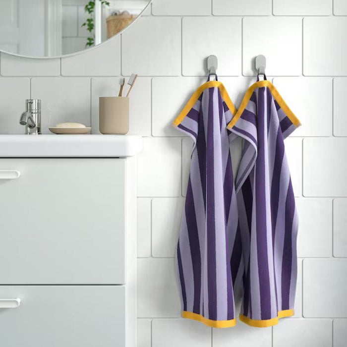 An image of a Lilac/Golden-Yellow hand towel hanging from a hook on a bathroom wall