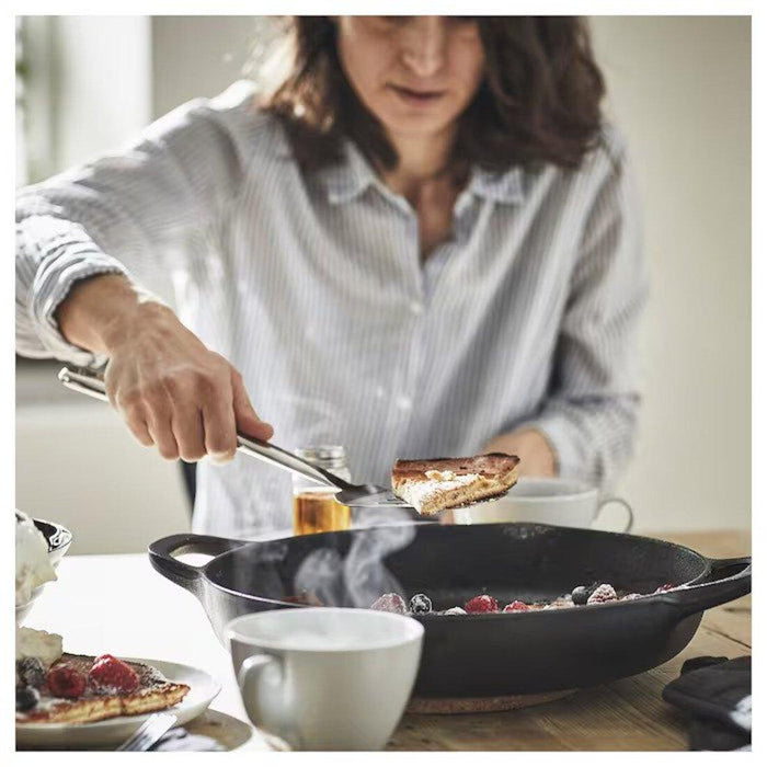 Person cooking in a kitchen with a pan on a stove