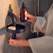 A person wearing a light-colored textured bathrobe holds a brown bottle with a pump dispenser, likely containing liquid soap or lotion.-90595992