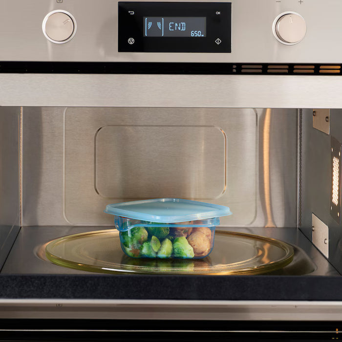 An IKEA PRUTA food container, 0.6 l (20 oz), with a blue lid, was placed inside a stainless steel microwave. The container holds Brussels sprouts and what appears to be meatballs. The microwave's digital display reads 'END' and '650,' signaling the cooking cycle completion-60597105 