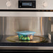 An IKEA PRUTA food container, 0.6 l (20 oz), with a blue lid, was placed inside a stainless steel microwave. The container holds Brussels sprouts and what appears to be meatballs. The microwave's digital display reads 'END' and '650,' signaling the cooking cycle completion-60597105 