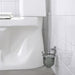 The wall-mounted chrome toilet brush holder is in a sleek bathroom setting, featuring white tiled walls, a modern toilet, and light-colored flooring for a clean aesthetic.- 90581551