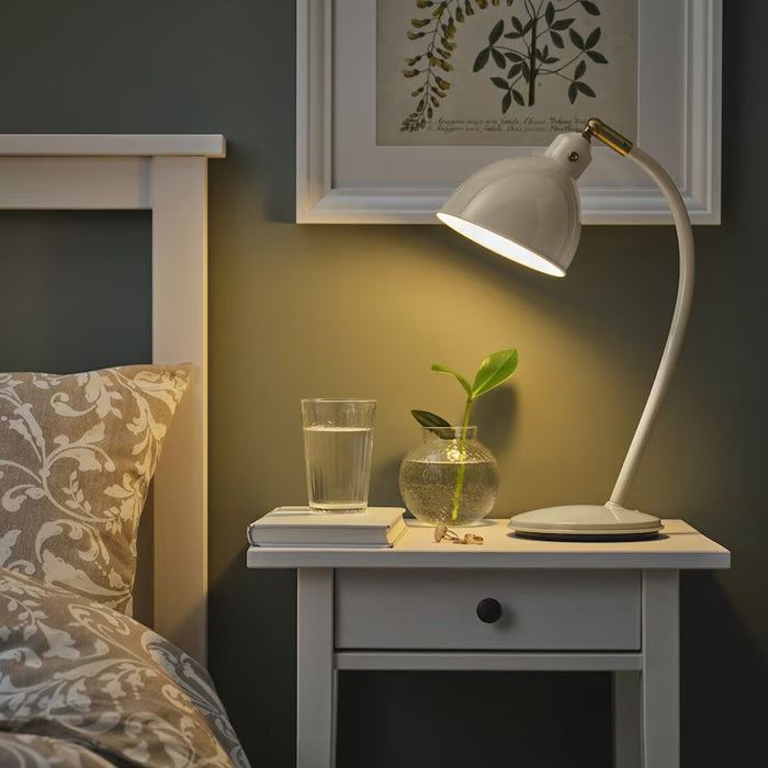 A stylish IKEA RÖDFLIK desk lamp in light beige with a vintage industrial design, featuring a shiny enamel-like finish, brass-colored accents, and an adjustable shade with a toggle switch for precise lighting control.20583921   