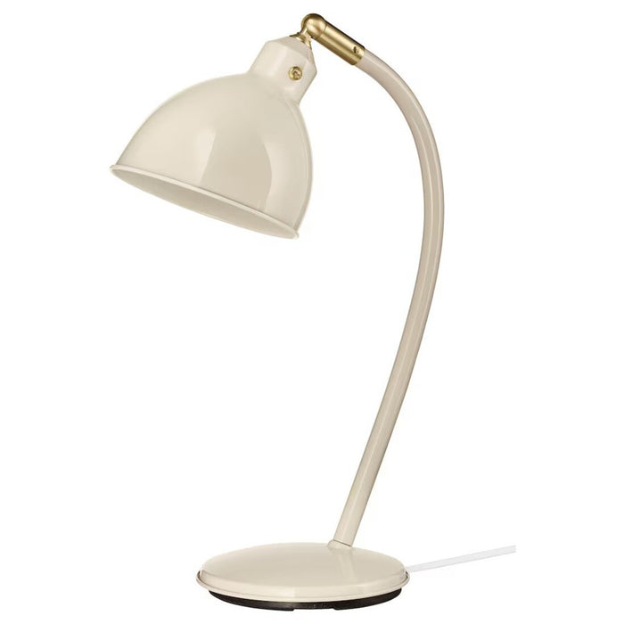 A stylish IKEA RÖDFLIK desk lamp in light beige with a vintage industrial design, featuring a shiny enamel-like finish, brass-colored accents, and an adjustable shade with a toggle switch for precise lighting control.
