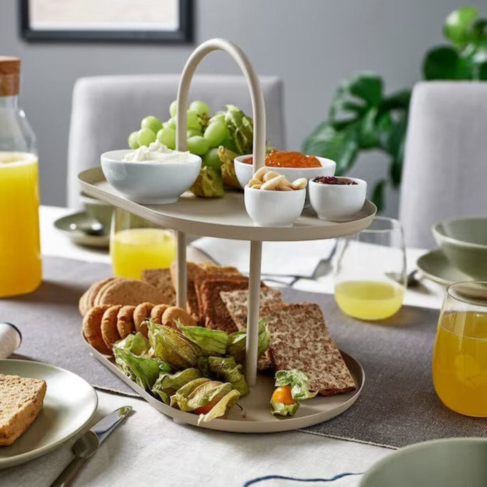 Enjoy snacks elegantly presented on the IKEA SOMMARÖGA Two-Tier Serving Stand, featuring a light grey-beige color for a touch of modern sophistication