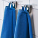 A close-up image of a simple and classic blue hand towel hanging on a bathroom hook