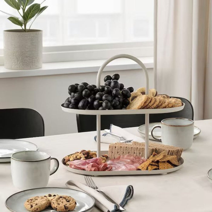 Enjoy snacks elegantly presented on the IKEA SOMMARÖGA Two-Tier Serving Stand, featuring a light grey-beige color for a touch of modern sophistication