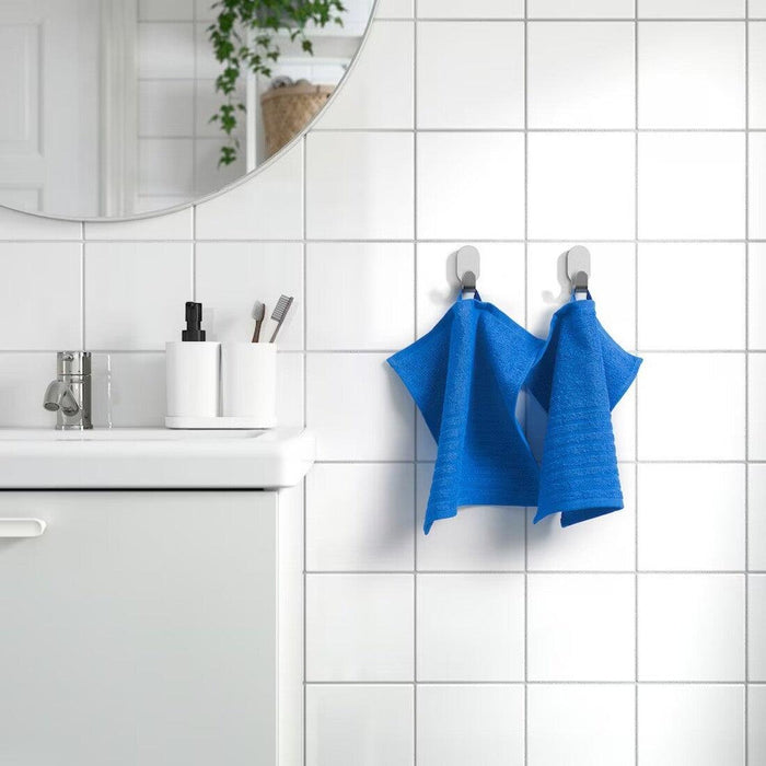 The cloth is neatly folded and placed on a wooden bathroom shelf, and its stylish color adds a pop of brightness to the scene.