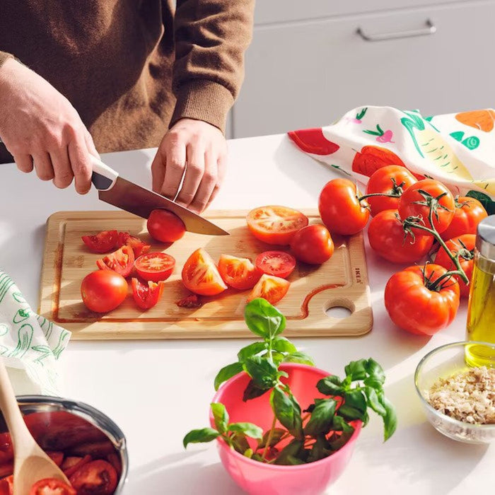 A person's hands using a knife to cut vegetables on a  chopping board from IKEA