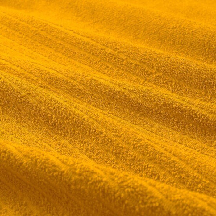 Close-up view of a textured, golden-yellow IKEA VÅGSJÖN washcloth, 30x30 cm, highlighting its soft and absorbent surface.90549518

