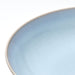 Close-up of light blue FÄRGKLAR stoneware plate showing handcrafted reactive glaze texture