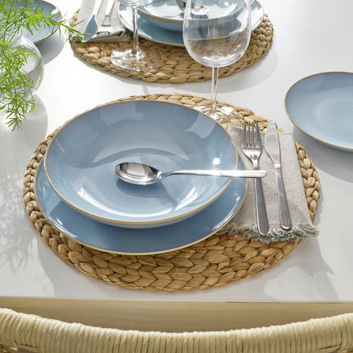 Light blue FÄRGKLAR plates and bowls set on woven mats with silverware for dining
