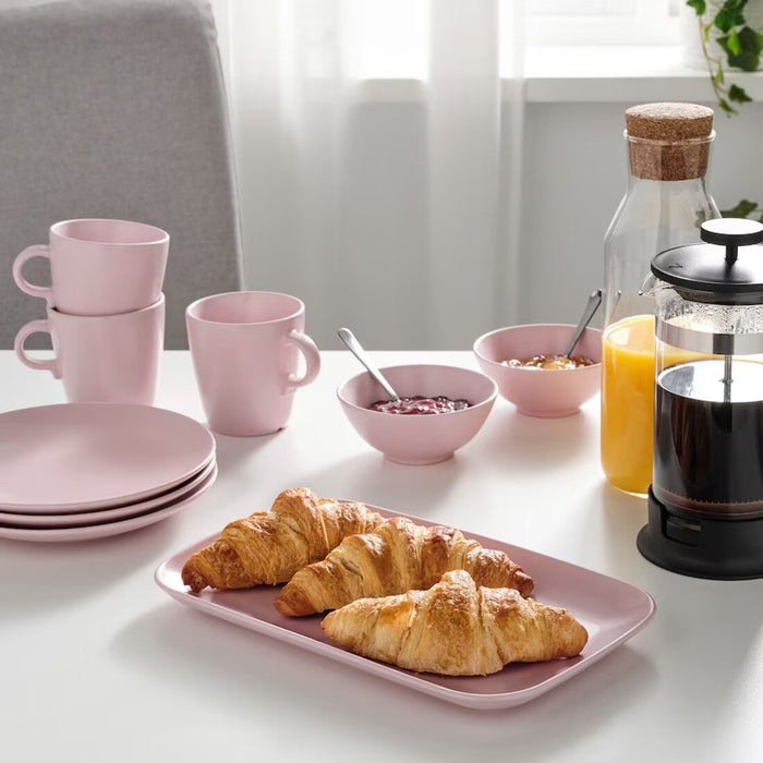 Dining table with pink IKEA FÄRGKLAR platters and matching dinnerware.