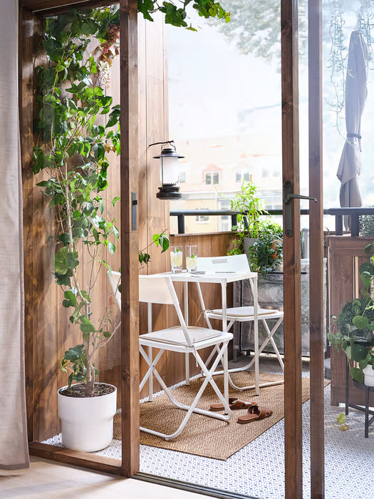  IKEA FEJAN white outdoor table and chairs on wooden deck with green plants sliding doors