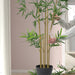 Hands arranging FEJKA bamboo plant showing green leaves and yellow stalks