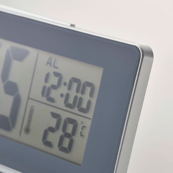 IKEA FILMIS grey LED alarm clock with backlight on, clear digital display showing time and temperature, close-up
