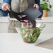 Person bending IKEA FINFÖRDELA chopping board to slide chopped onions into a salad bowl