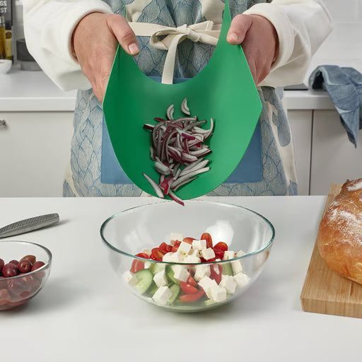 Person holding bent IKEA FINFÖRDELA green chopping board funnelling chopped red onions into salad bowl