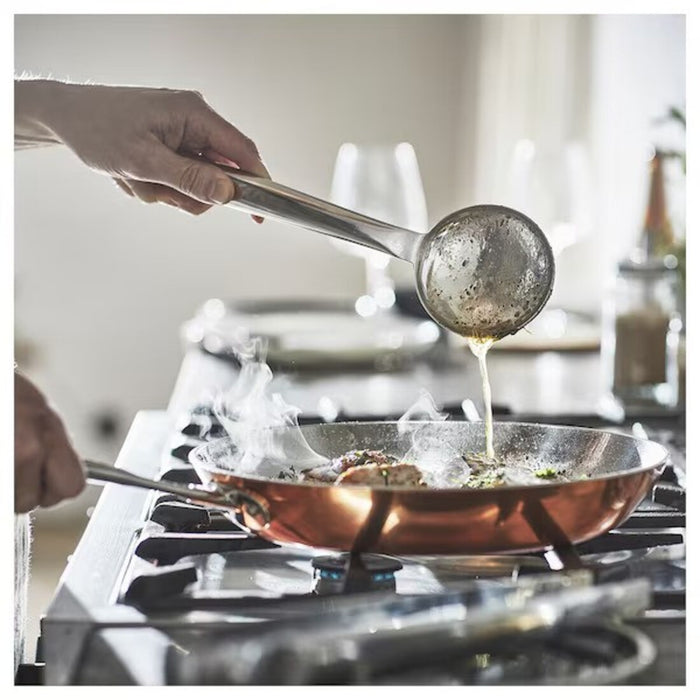 Close-up of copper-colored IKEA OUMBÄRLIG Frying Pan, 28 cm (11") on stove