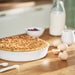 Baked dish in IKEA FISKTÄRNA white ceramic pie plate surrounded by eggs milk and berries