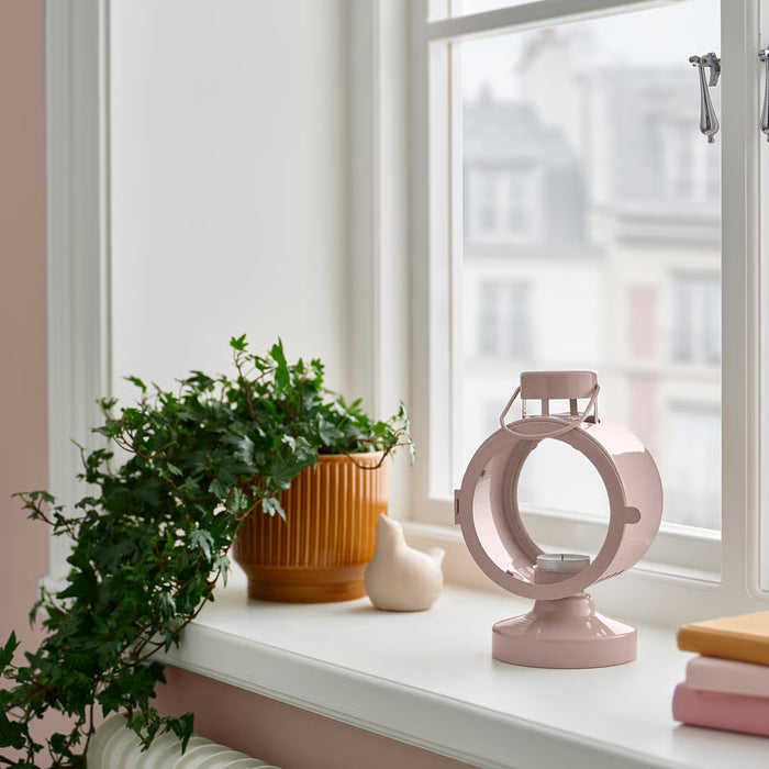 IKEA FLODSVALA pale pink lantern with tealight glowing warm light on table indoor setting