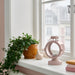 IKEA FLODSVALA pale pink lantern with tealight glowing warm light on table indoor setting