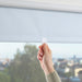 Hand adjusting IKEA FÖNSTERBLAD cordless white roller blind showing smooth silent operation