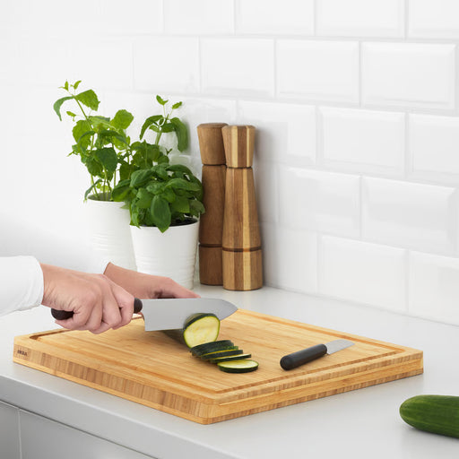 Person slicing cucumber on wooden cutting board using IKEA FÖRDUBBLA grey knife set in an Indian kitchen