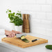 Person slicing cucumber on wooden cutting board using IKEA FÖRDUBBLA grey knife set in an Indian kitchen