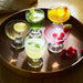 IKEA FRUKTDUVA goblets filled with colourful cocktails garnished with fruit on a wooden tray