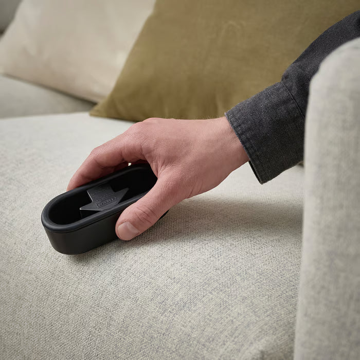 Hand using the IKEA FRUKTPLOCKARE lint brush on a couch to clean fabric fibres