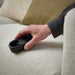 Hand using the IKEA FRUKTPLOCKARE lint brush on a couch to clean fabric fibres