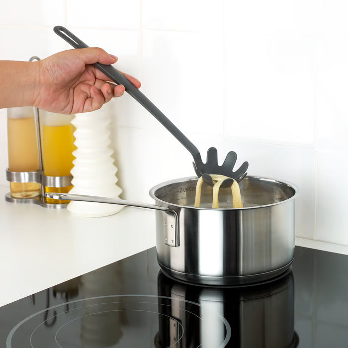  Hand using IKEA FULLÄNDAD grey spoon to stir contents of a saucepan on a hob