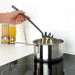  Hand using IKEA FULLÄNDAD grey spoon to stir contents of a saucepan on a hob